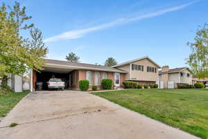 Split level home featuring a front lawn, an attached carport, and concrete driveway