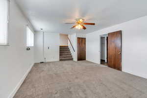 Interior space featuring baseboards, stairway, carpet floors, and ceiling fan