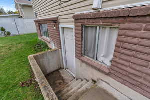 View of side of home with fence and a lawn