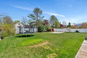 View of yard featuring an outbuilding, a fenced backyard, a trampoline, a patio area, and a shed