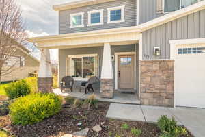 Entrance to property with a porch, board and batten siding, and stone siding
