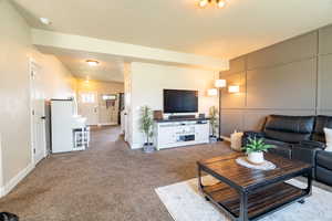 Carpeted living area with baseboards, accent wall