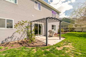 Rear view of house with a pergola, a lawn, a patio area, and a trampoline