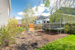 View of yard featuring a trampoline, fence, and a mountain view
