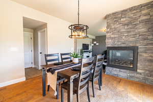 Dining area featuring baseboards, a fireplace, wood finished floors, and an inviting chandelier