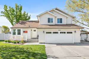 Traditional-style home featuring driveway, fence, an attached garage, a shingled roof, and a front yard