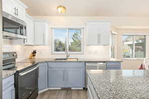 Kitchen with backsplash, appliances with stainless steel finishes, a sink, and plenty of natural light