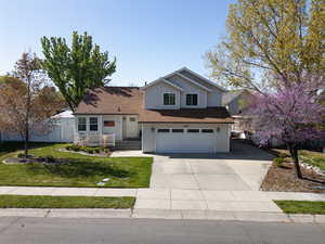 Traditional-style house with roof with shingles, concrete driveway, fence, a garage, and a front yard