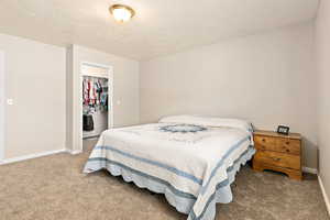 Carpeted bedroom featuring a walk in closet, baseboards, and a closet