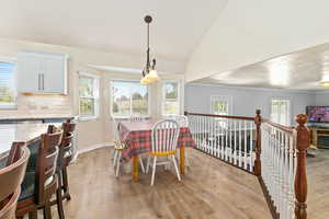 Dining room with vaulted ceiling, light wood finished floors, and baseboards