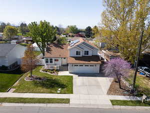 Traditional-style house with solar panels, concrete driveway, a garage, a shingled roof, and a front yard