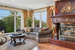 Family  room featuring recessed lighting, wood finished floors, ornamental molding, gas fireplace and expansive windows for view