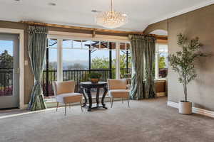 Primary Bedroom sitting room with carpet floors, baseboards, ornamental molding, and an inviting chandelier.  Exit to Primary Deck & Patio