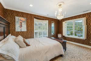 Bedroom featuring an inviting chandelier, crown molding, wallpapered walls, and visible vents