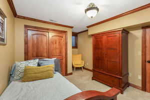 Bedroom featuring light colored carpet, baseboards, ornamental molding, and visible vents