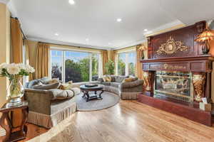 Living room featuring a fireplace, wood finished floors, crown molding, and recessed lighting