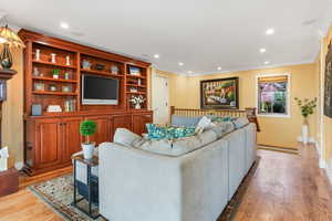 Living room with baseboards, wood finished floors, recessed lighting, and crown molding