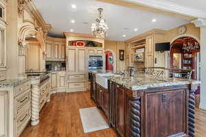 Kitchen with open shelves, a sink, a chandelier, arched walkways, and cream cabinetry