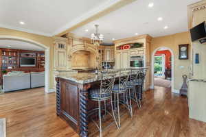 Kitchen with arched walkways, stainless steel oven, cream cabinetry, and recessed lighting