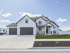 Modern farmhouse style home featuring driveway, board and batten siding, a front yard, fence, and a porch