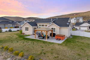 Rear view of property featuring a fenced backyard, a mountain view, a gazebo, a patio area, and a hot tub