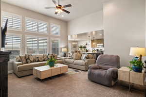 Living area featuring recessed lighting, a high ceiling, light carpet, and ceiling fan with notable chandelier