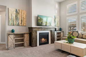 Carpeted living area with a fireplace and a high ceiling