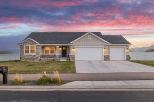 View of front of house with stone siding, an attached garage, driveway, and a front yard