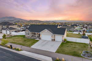 View of front facade featuring stone siding, fence, a residential view, and a garage