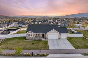 View of front of house with driveway, stone siding, a porch, a garage, and a residential view