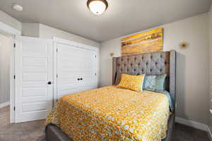 Carpeted bedroom featuring a textured ceiling, a closet, and baseboards