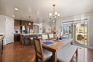 Dining space with a notable chandelier, dark wood-style floors, and recessed lighting
