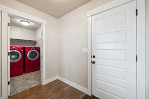 Laundry room with washing machine and clothes dryer, a textured ceiling, baseboards, dark wood-type flooring, and laundry area