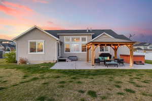 Back of property with a gazebo, an outdoor living space, a patio area, a hot tub, and stucco siding