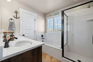 Full bath with a shower stall, double vanity, a sink, a bath, and stone finish flooring