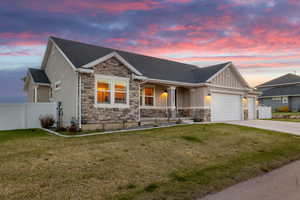View of front of house with stone siding, driveway, fence, and a garage