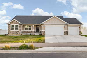 Craftsman-style house featuring a front lawn, stone siding, and a garage