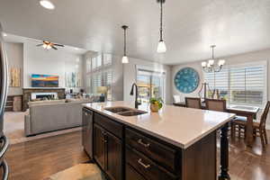 Kitchen featuring a textured ceiling, stainless steel dishwasher, dark wood-style flooring, and a sink