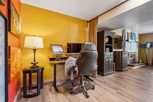 Office space with baseboards, wood finished floors, and a fireplace