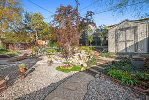 View of yard featuring an outdoor structure, a storage unit, and fence