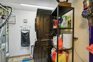 Laundry area featuring baseboards, stacked washing maching and dryer, and laundry area