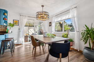 Dining space featuring wood finished floors, a textured ceiling, baseboards, and a notable chandelier