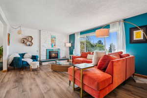 Living room featuring a fireplace, wood finished floors, and a textured ceiling