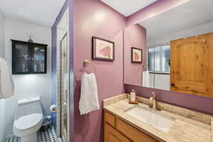 Bathroom featuring toilet, vanity, and a shower