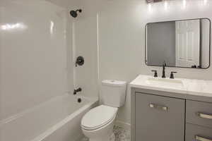 Full bath with tile patterned flooring, toilet, vanity, baseboards, and  shower combination