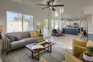 Living room with recessed lighting, light wood-style floors, and ceiling fan with notable chandelier