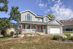 Traditional home featuring a front lawn, a porch, concrete driveway, and stucco siding