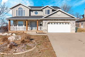 Traditional-style house with roof with shingles, driveway, a porch, an attached garage, and stucco siding