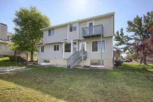 Rear view of property with fence, a lawn, and a balcony