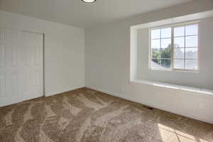Carpeted spare room featuring baseboards and visible vents